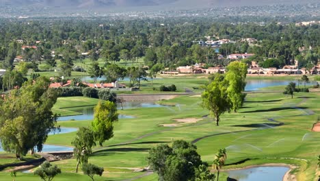 a green golf course in scottsdale, arizona with lakes and sprinklers