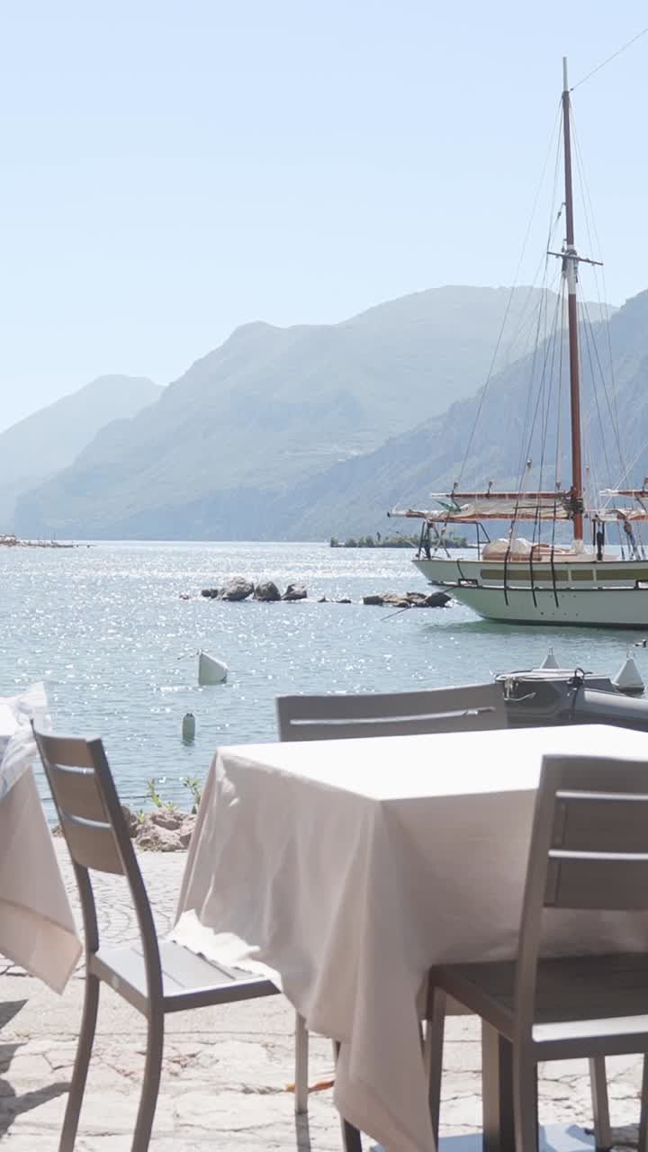Scenic View from vacant lakeside restaurant table to anchored yacht