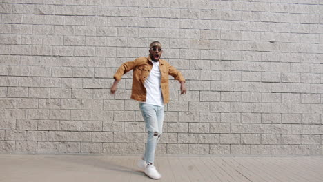 man dancing in front of a brick wall