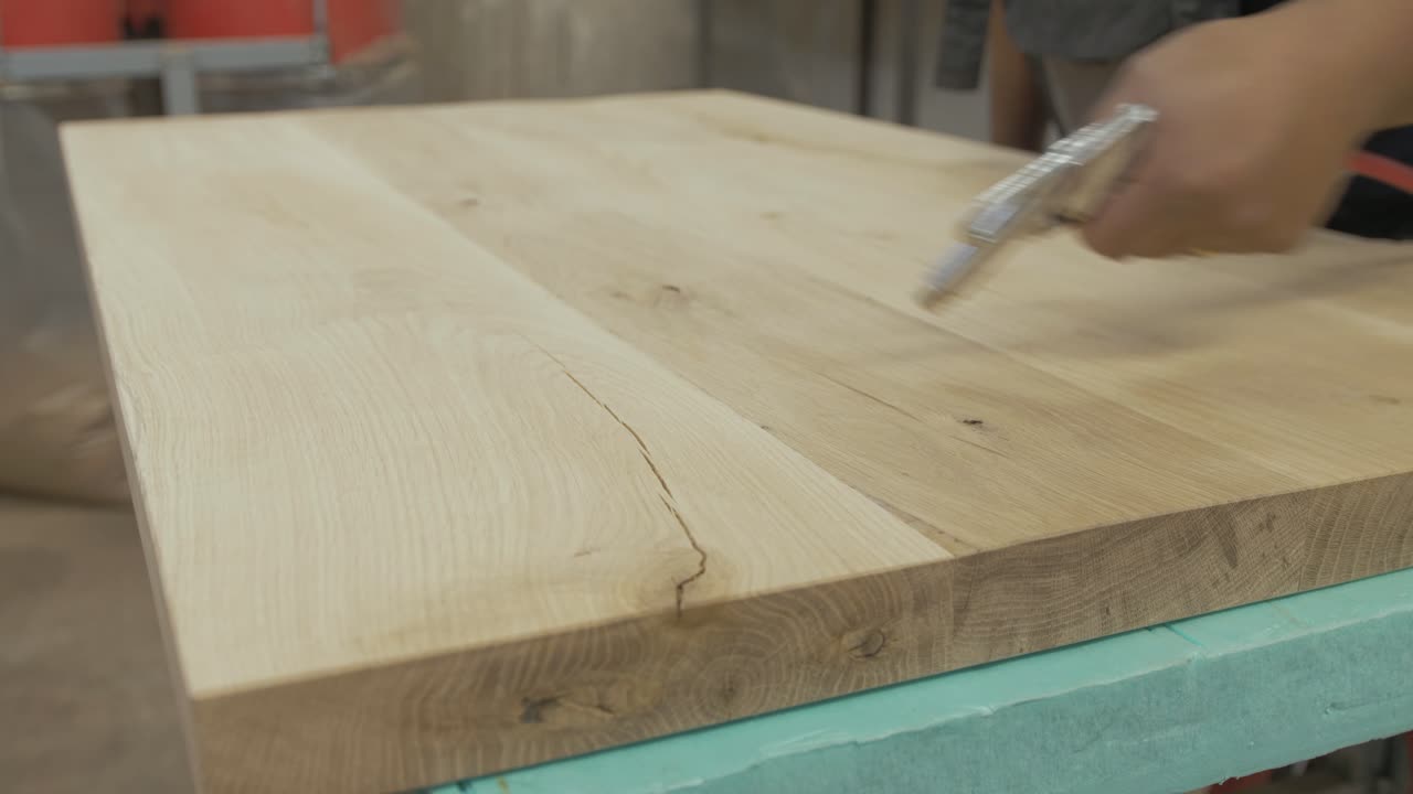 Blowing off sawdust particles white oak tabletop. Medium Close Up