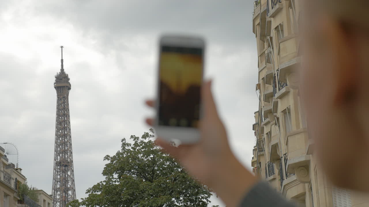 mujer tomando una foto de estilo retro de la torre eiffel con un móvil