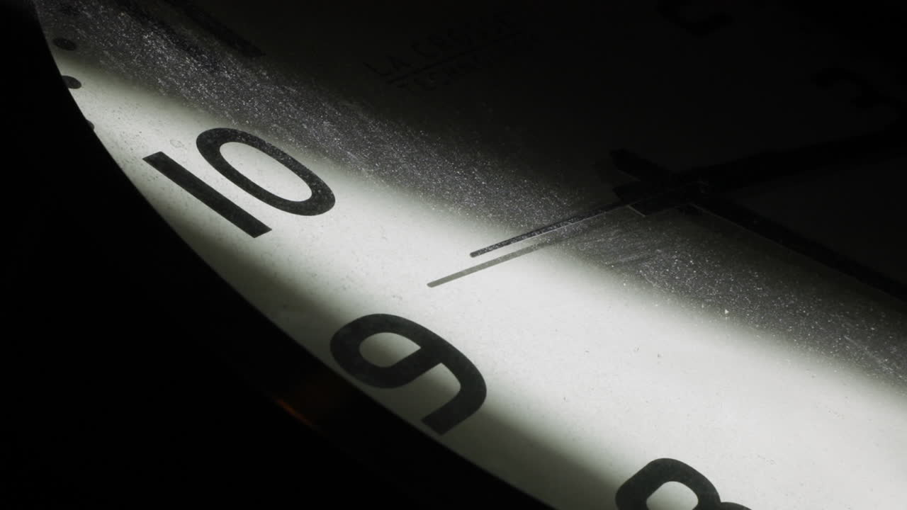 Close up shot of vintage clock lighting in dark room with second hand in motion with dusty glass surface