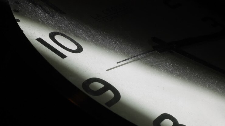 Close up shot of vintage clock lighting in dark room with second hand in motion with dusty glass surface