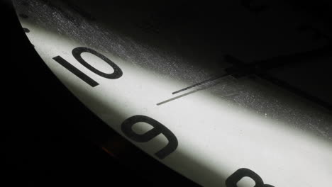 Close-up-shot-of-vintage-clock-lighting-in-dark-room-with-second-hand-in-motion-with-dusty-glass-surface