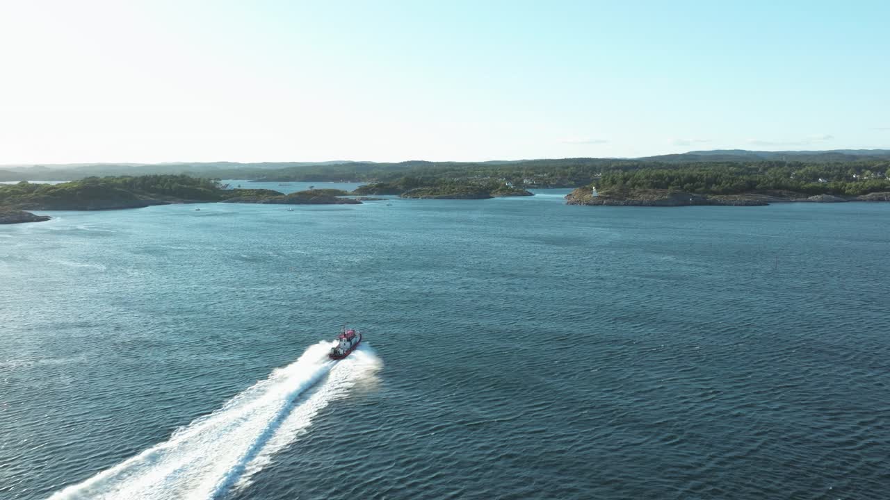 A speedboat moves swiftly across the tranquil water, surrounded by rocky shores and lush greenery. The scene captures the peaceful beauty of a summer evening by the coast