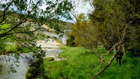 Wide-shot-of-woman-walking-along-water-stream-during-windy-day