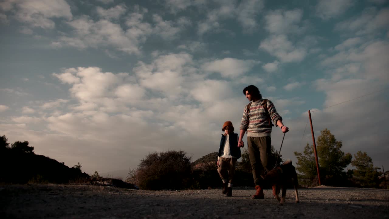 Young father and son trekking with dog on nature footpath