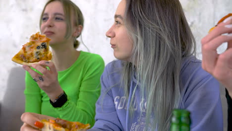 cuatro amigas riendo y comiendo pizza en casa