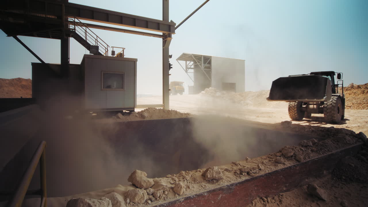 Industrial sand mining - Loader working at sand area. Dolly left, loading and dumping sand into a mill, Industrial machinery at sand quarry. 4K footage.
