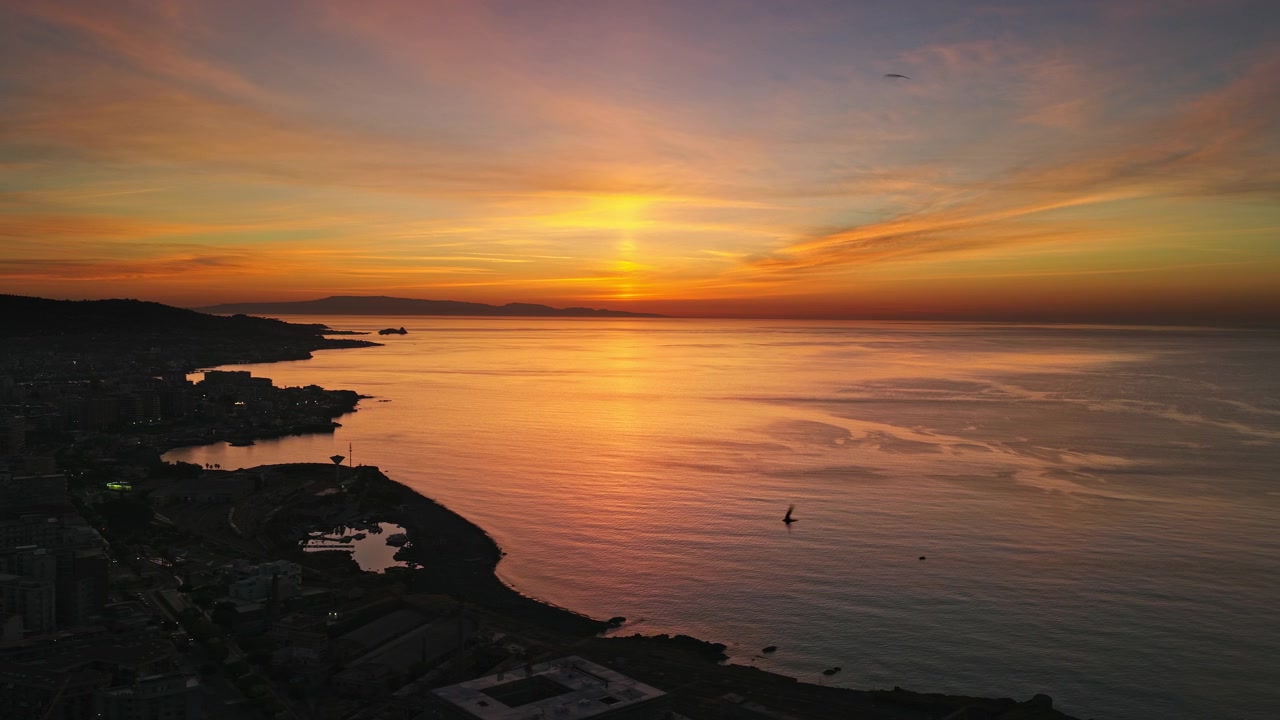 La ciudad portuaria de Catania silueteada a lo largo de la costa este de Sicilia, Italia, con vistas al mar Jónico durante la tarde. Toma aérea.