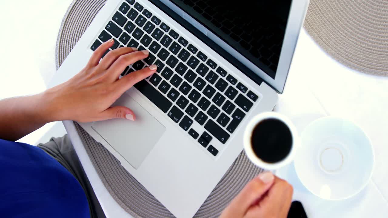 woman using laptop and putting down coffee