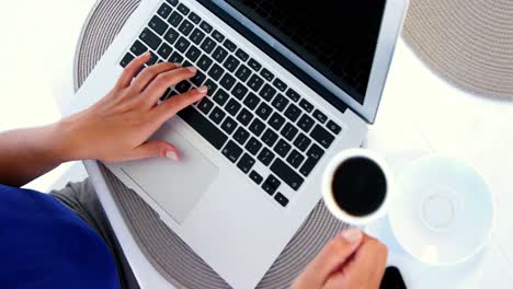 woman-using-laptop-and-putting-down-coffee