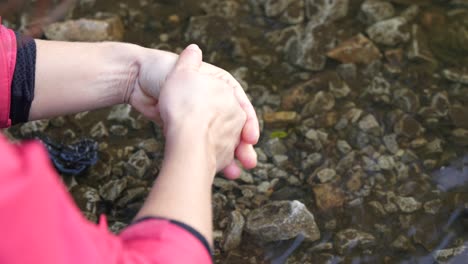 Close-up-of-a-woman-washing-hands-in-a-stream,-outside,-in-the-English-Countryside,-in-Slow-Motion