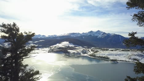 Fly-past-kids-sitting-on-rock-to-frozen-lake-and-mountains