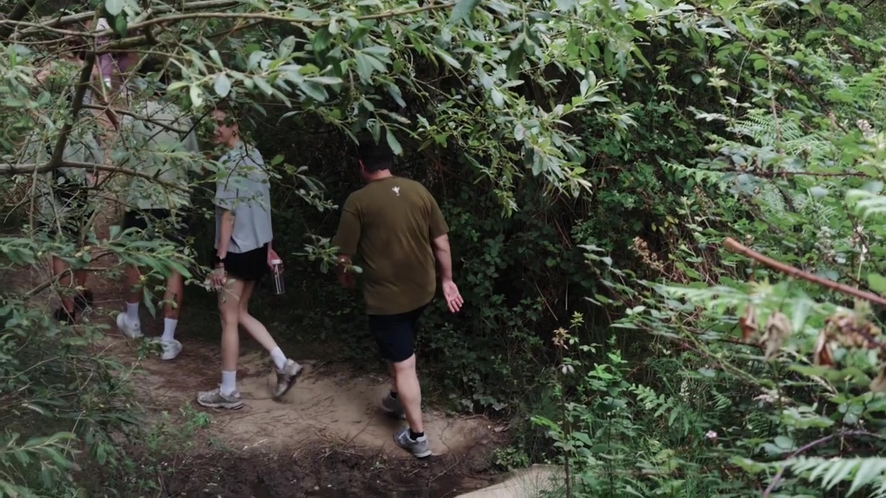 Grupo de personas caminando por un sendero de tierra, rodeados de densa vegetación verde, explorando la naturaleza y disfrutando de un estilo de vida saludable