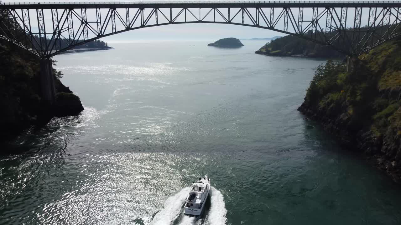 un dron cinematográfico vuela bajo siguiendo un barco en un puente de paso engañoso en anacortes, washington, ee. uu. en un día soleado de primavera