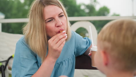 a loving moment between a mother and her young son outdoors, the mother, smiling warmly, collects an ice cream cone from her child