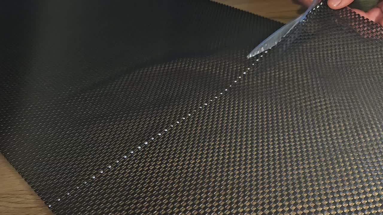 Scissors cutting black plastic mats on ground