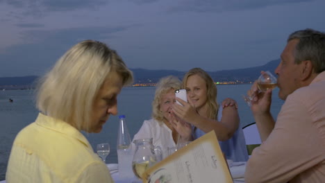 family spending evening in outdoor cafe at seaside