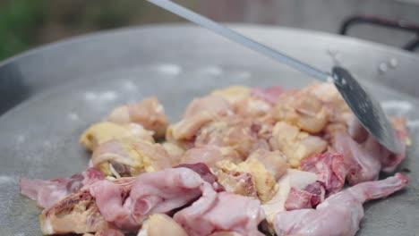 cooking raw chicken pieces in a large frying pan