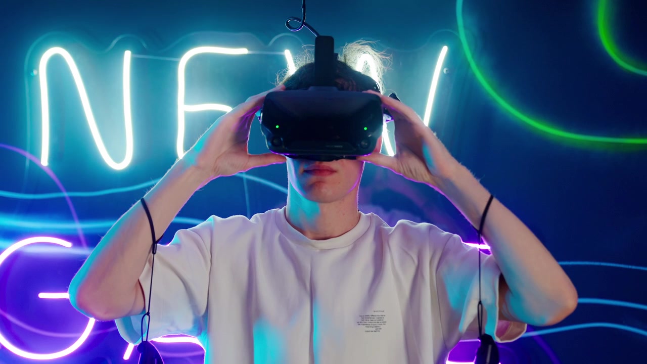 Giovane uomo indossa un visore per realtà virtuale in una stanza illuminata al neon