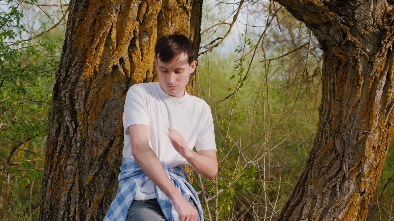 숲 속 의 나무 에 기대어 서 있는 젊은 남자