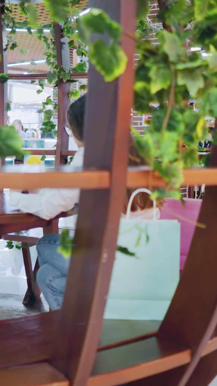 고급스러운 식당에서 vip 좌석에 앉아있는 여성, 주변 사람들과 함께 드폰에 집중하고, 디지털 조명이 배경에서 박이고, 트렌디한 레스토랑에서 활기찬 분위기를 만니다.