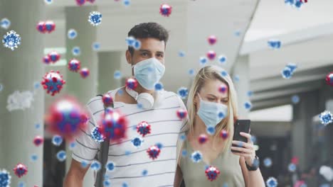 animation of virus cells over aucasian couple wearing face masks using smartphones