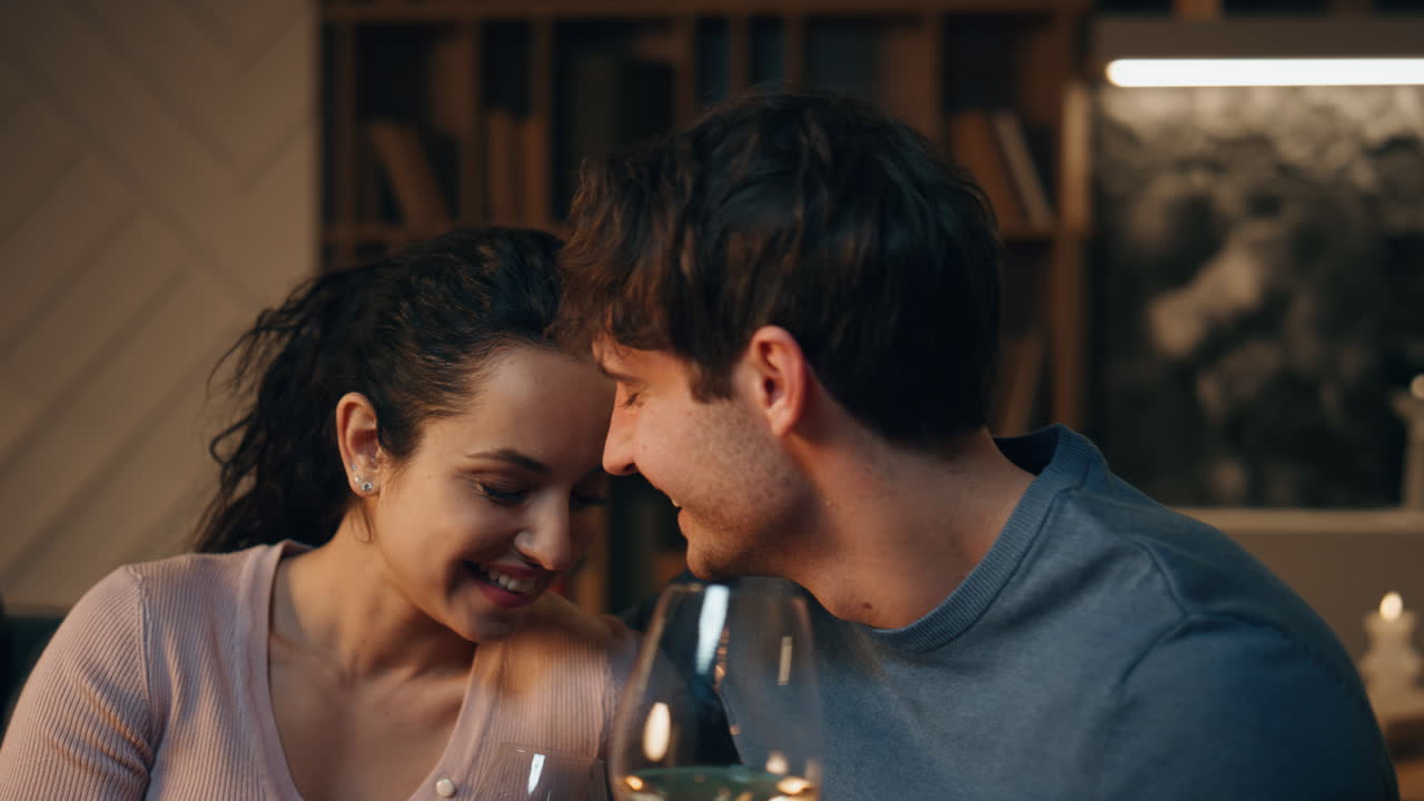 만적 인 파트너가 와인을 마시고 웃으며 집에서 함께 재미를 느끼고 있습니다.