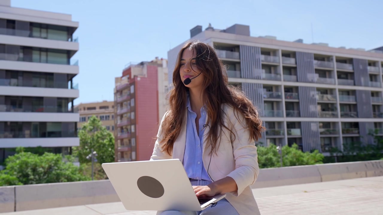 Joven empresaria en videollamada con portátil en la ciudad
