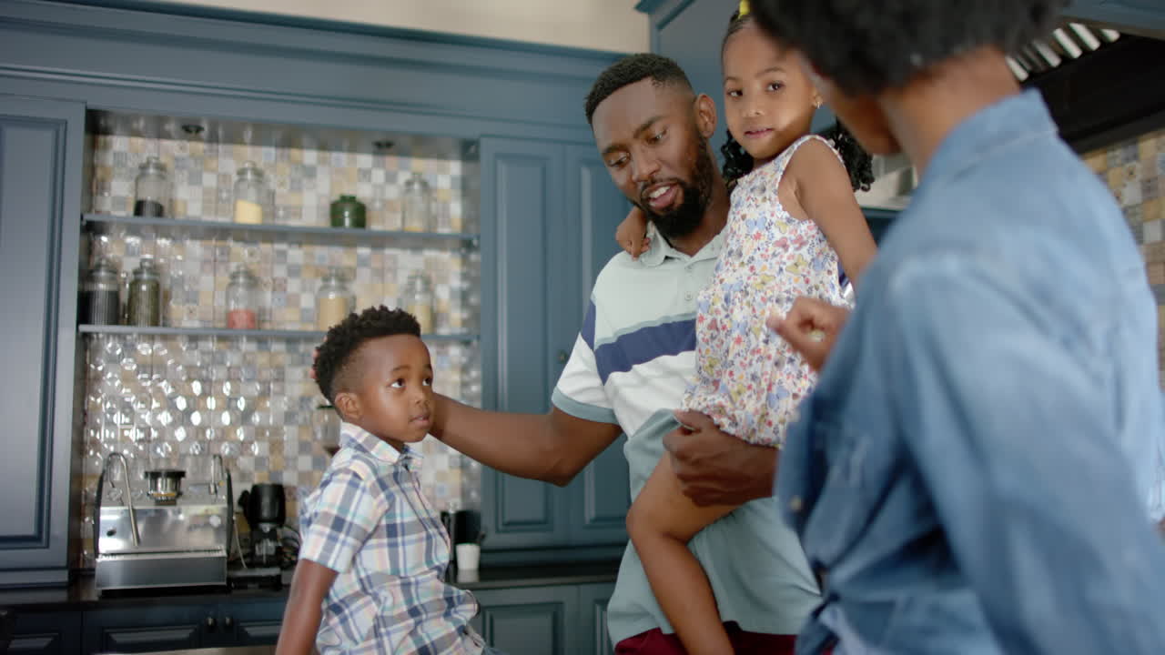 Famiglia afroamericana felice che parla e cucina in cucina, al rallentatore