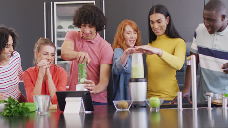 un grupo feliz de amigos diversos preparando una bebida saludable en la cocina juntos