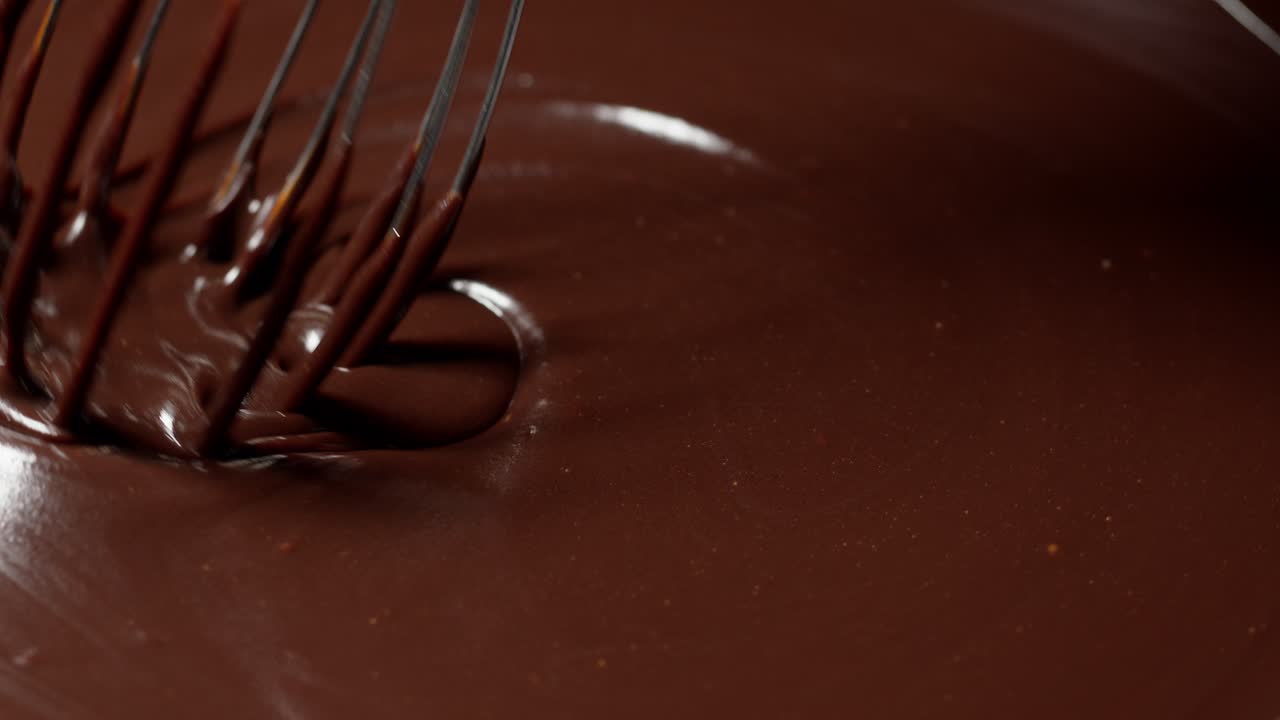 mezcla, agita el chocolate oscuro líquido derretido con batido, el confitero prepara el postre, la cubierta