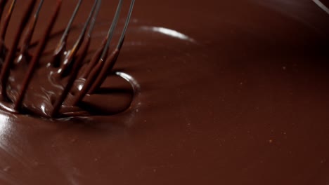 Mixing,-stirring-melted-liquid-dark-chocolate-with-whisk,-confectioner-prepares-dessert,-topping