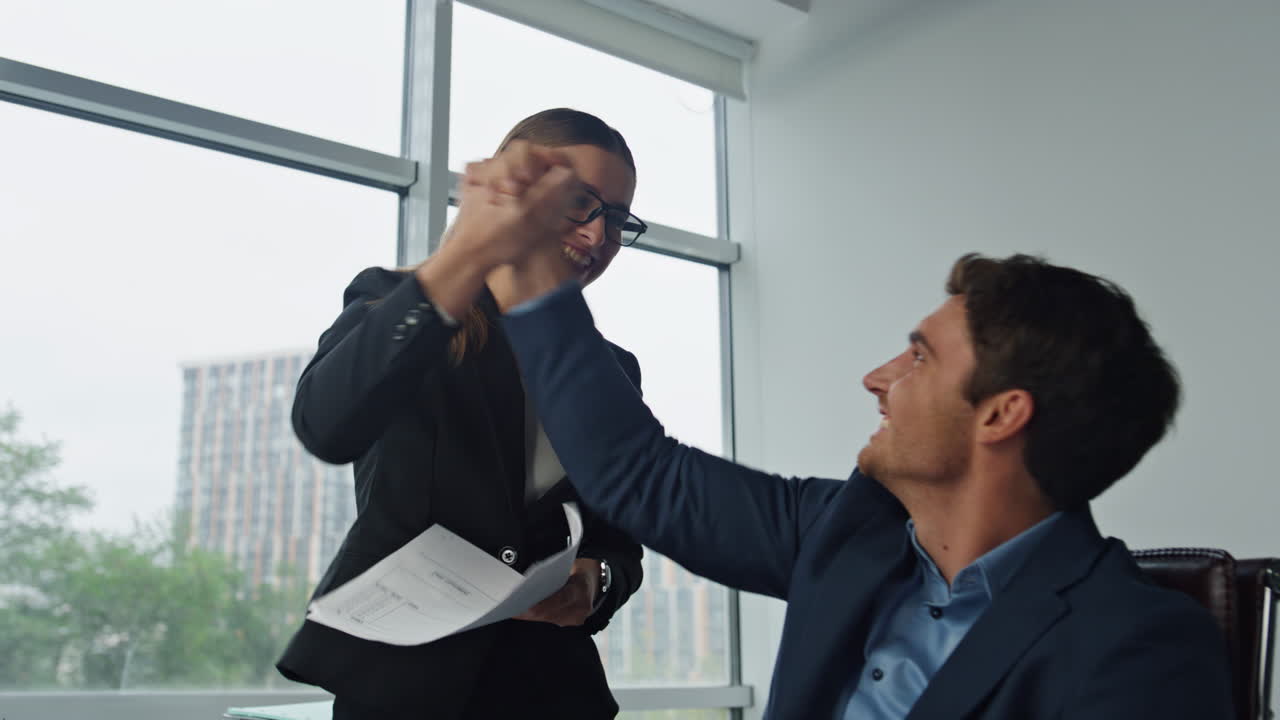 Gerentes sorrindo jogando papéis no escritório. Dois gerentes celebrando contrato.