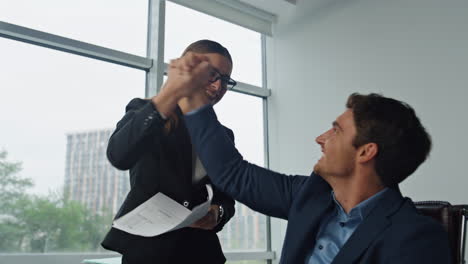 smiling managers throwing papers in office. two managers celebrating contract