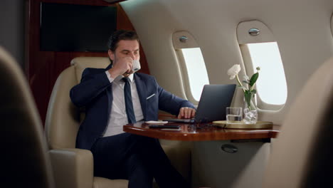 finance manager take sip of coffee on business trip. confident boss work laptop