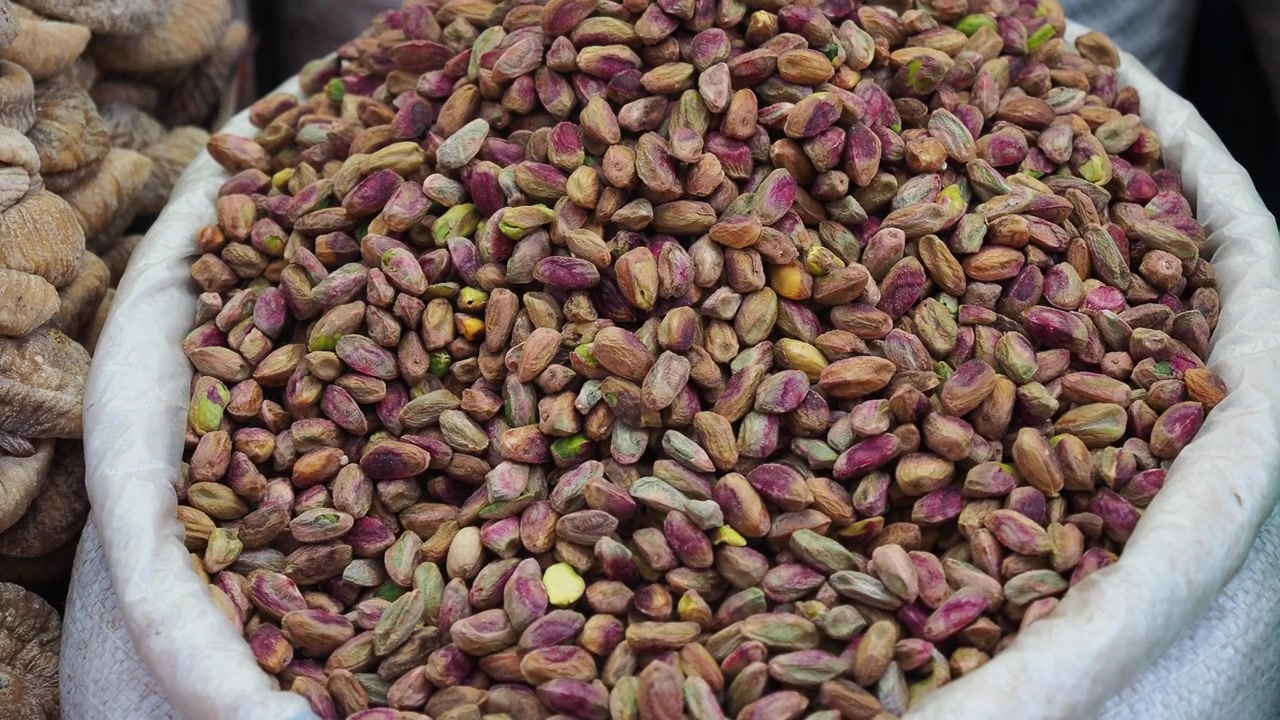 Pistacchi sgusciati colorati ammucchiati in un sacco in un mercato.