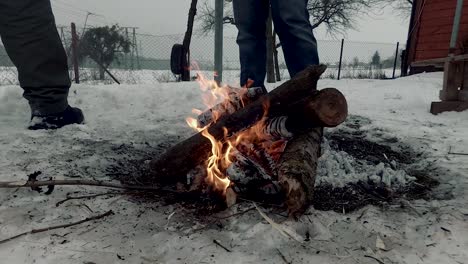 a bonfire in winter near the house, with two men