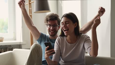 pareja mira la pantalla del teléfono celular grita de alegría celebra el éxito