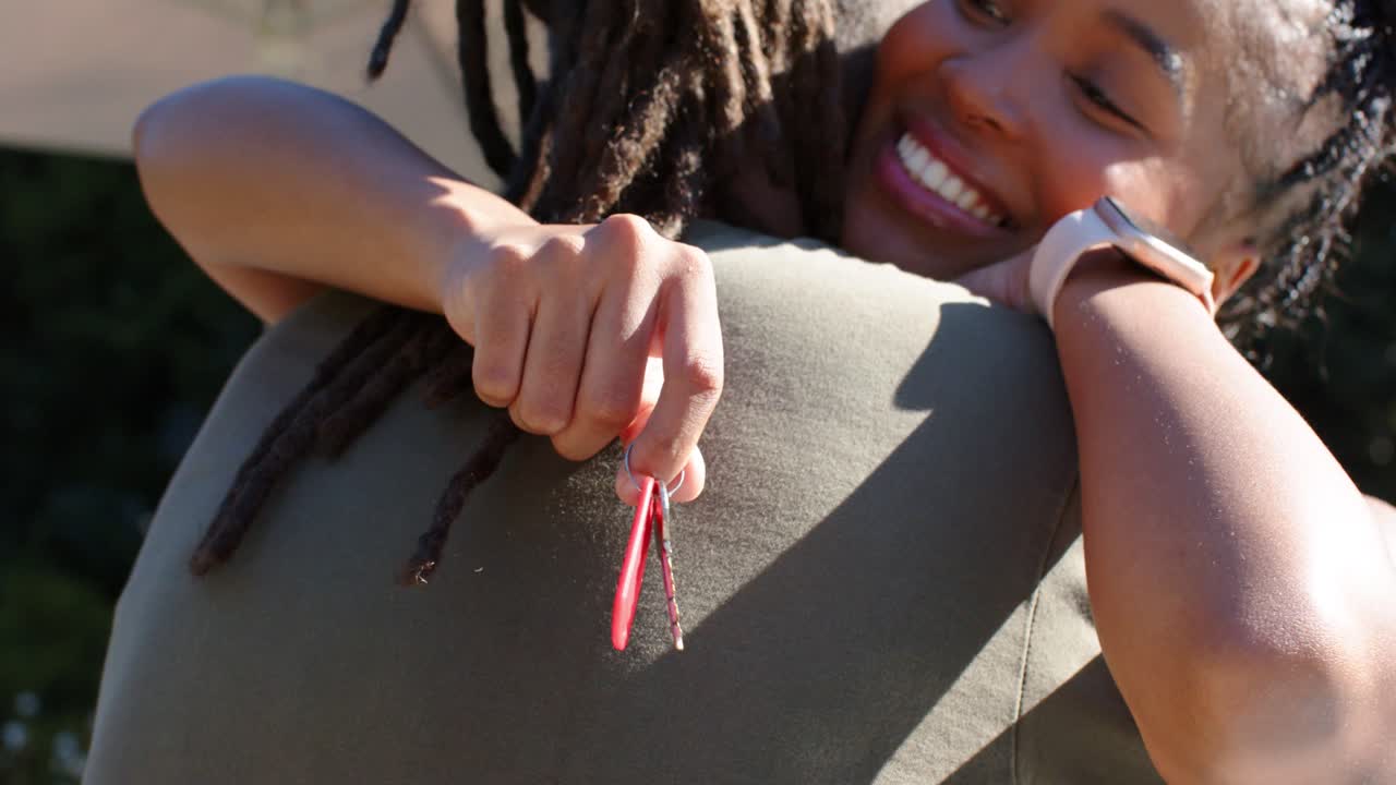 Donne afroamericane che si abbracciano, la stretta si rilassa, un portachiavi rosso che oscilla, una donna che saluta con l'orologio all'aperto