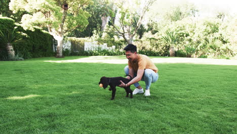 asian man playing with dog in sunny park, enjoying outdoor fun together, copy space