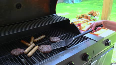 woman filliping hamburger on an outdoor grill on a sunny summer day