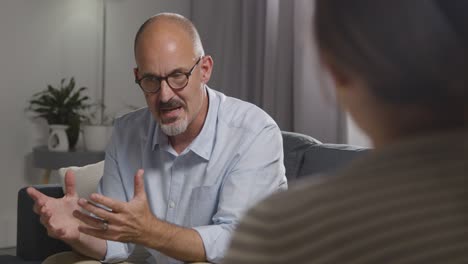 mature man sitting on sofa talking with female counsellor about general or mental health issue 18