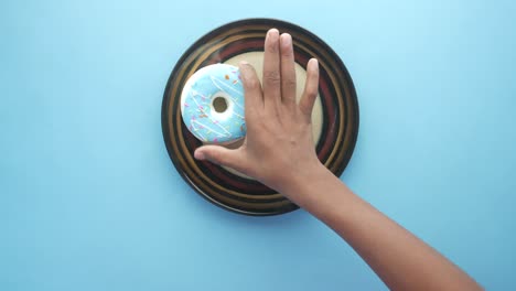 hand reaching for a donut on a plate