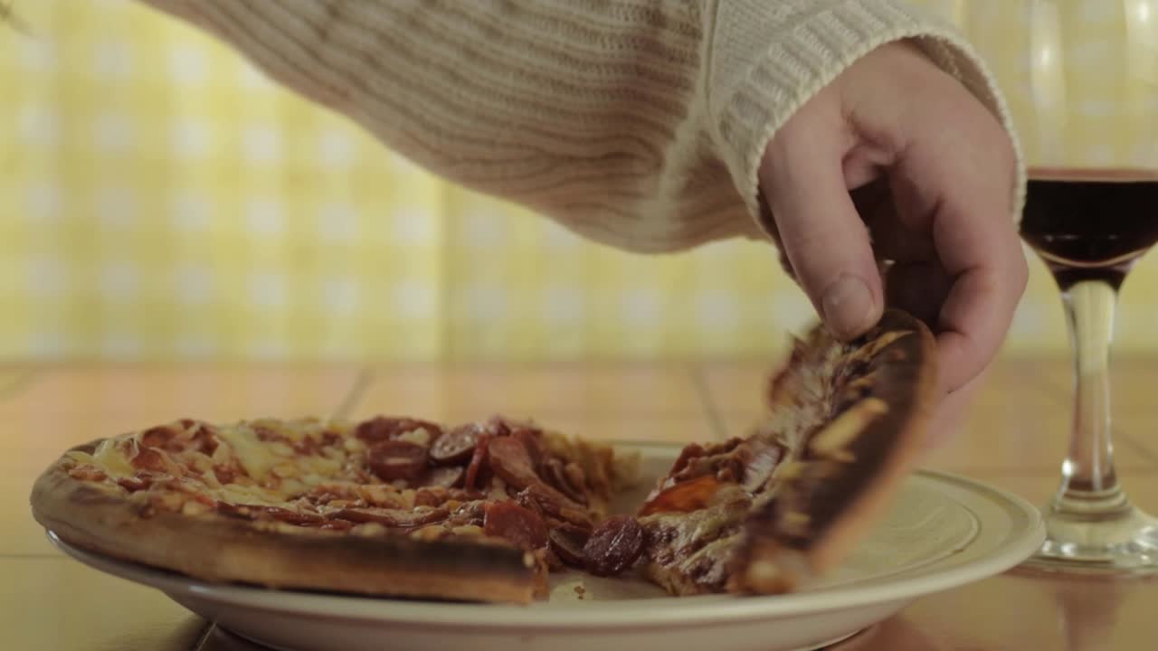 mano con copa de vino tinto y pizza de pepperoni tiro medio