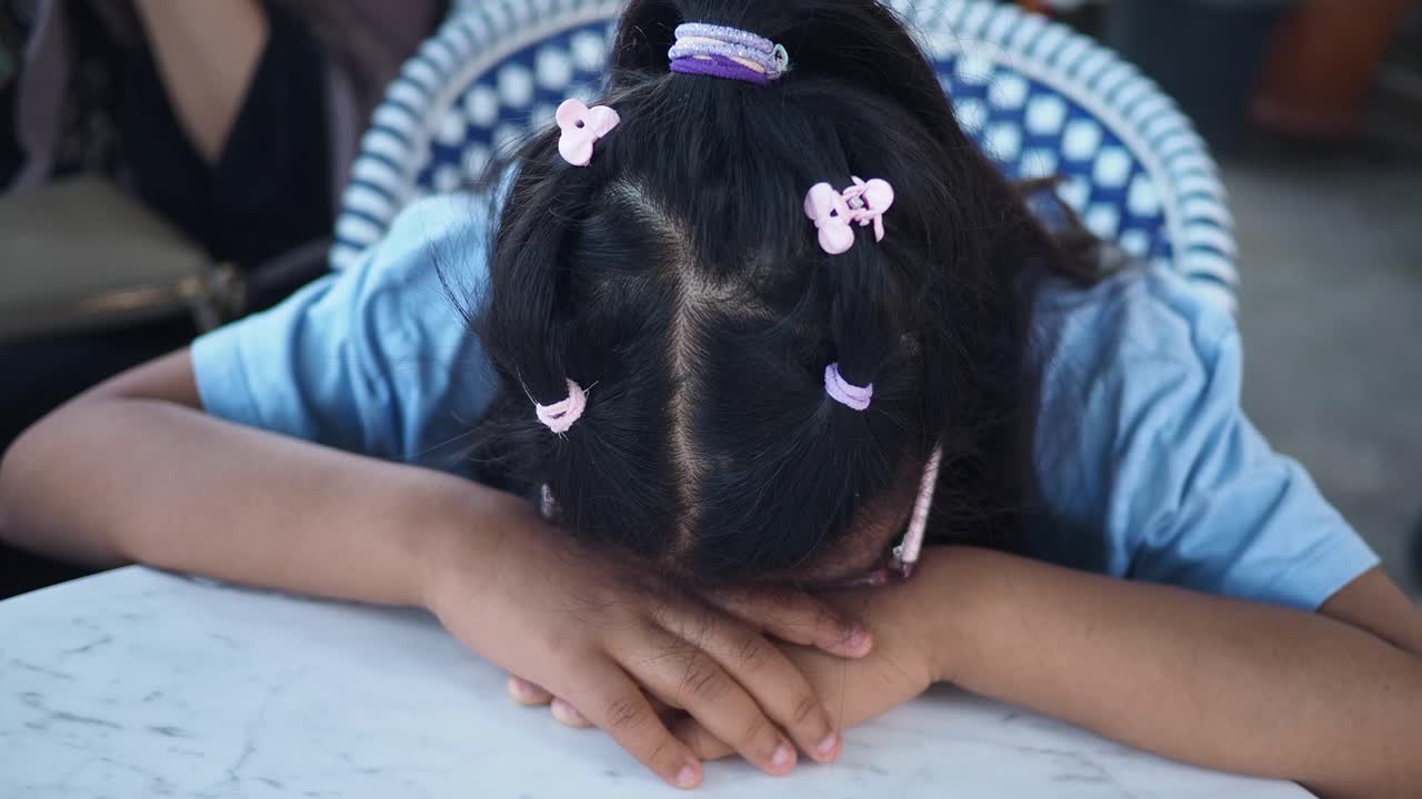 A young girl rests her head on a table