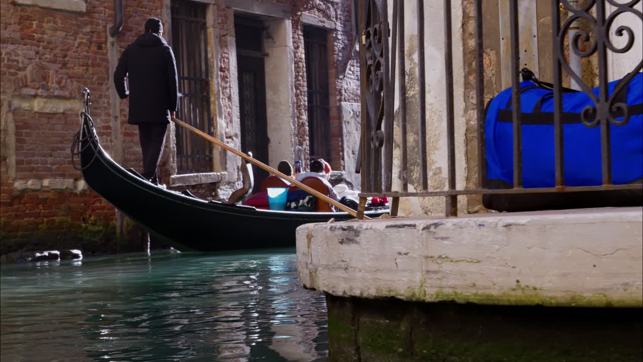 Gondolier ramant une gondole traditionnelle à travers un canal étroit de Venise