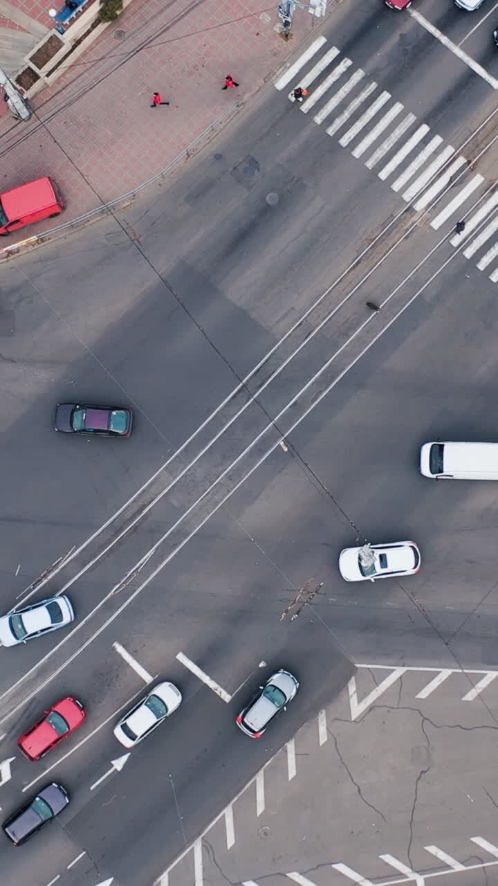 Aerial view of vehicles on city highway intersection. Traffic of cars and pedestrians. Vertical video