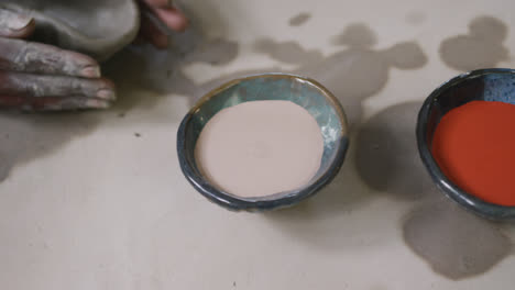 close up view of female potter working on clay to create pot at pottery studio